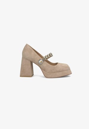 Beige suède blockhak schoenen met een ronde neus, voorzien van een decoratieve band versierd met stenen en een ronde knoopaccent.