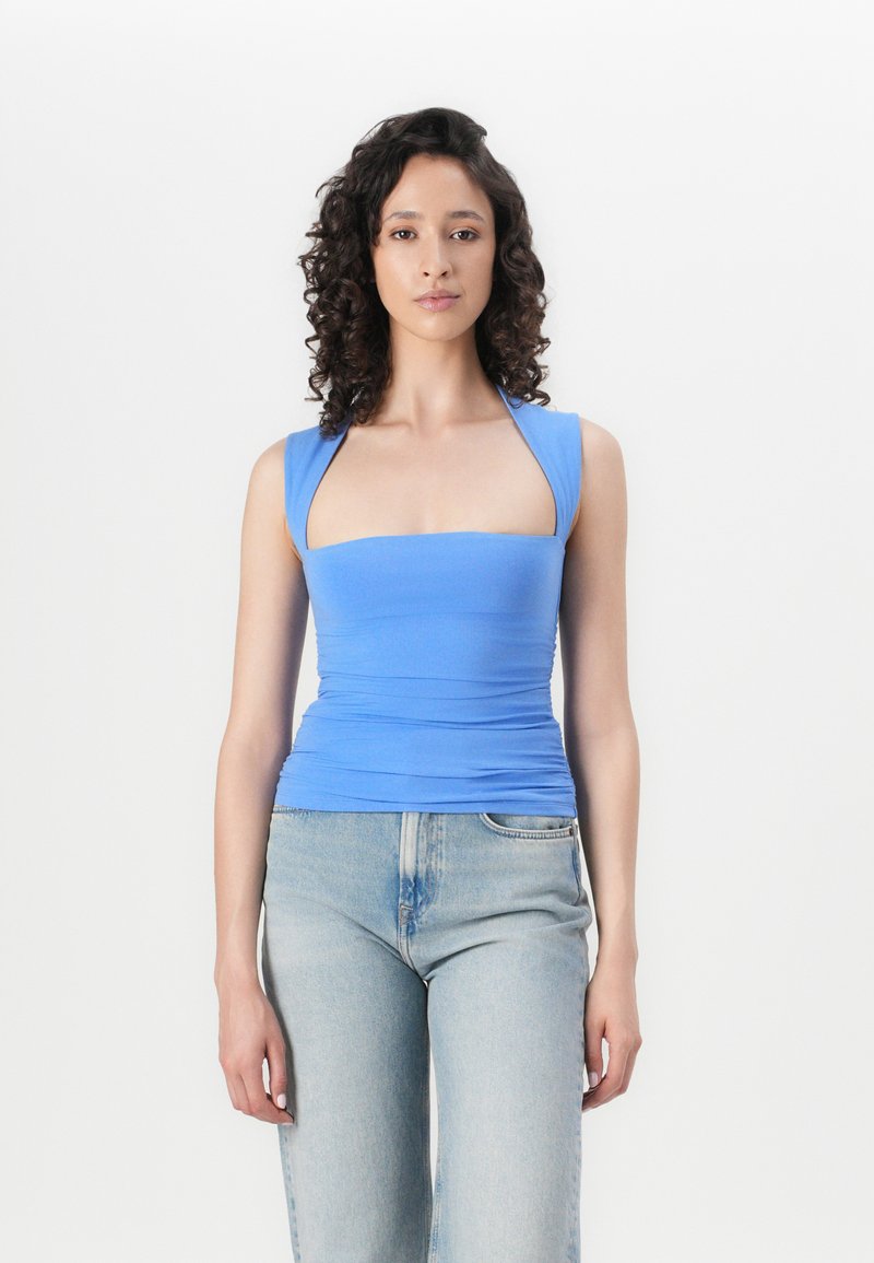 Top ajustado de tirantes anchos en azul elástico con escote cuadrado, combinado con jeans de mezclilla azul claro. Textura suave, diseño minimalista.