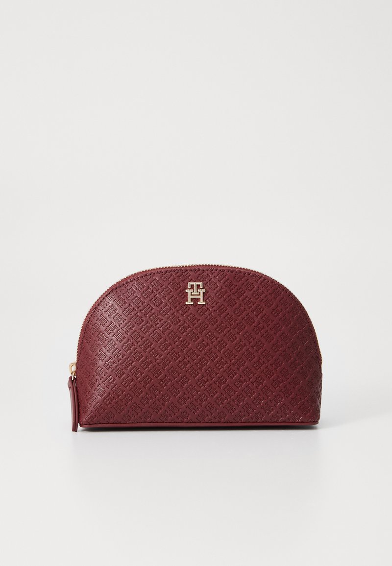 Burgundy textured zippered pouch with gold logo accent, rounded top, and embossed pattern on faux leather material. Compact design.