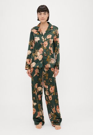 Blomstermönstrad satinpyjamasuppsättning i mörkgrön, med lång ärm, krage och vida byxor, prydd med stora rosa och lila blommor.