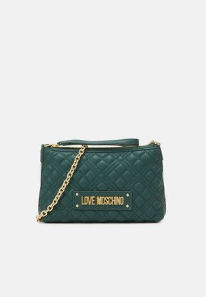 Green quilted handbag with gold chain strap, featuring a gold logo plate on the front and a zippered top closure.