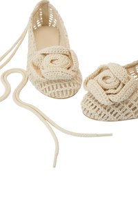 Zapatos de punto beige tipo slip-on con un diseño de flor en la puntera, con un patrón de rejilla transpirable y cordones a juego.