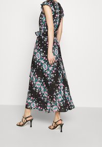 Svart klänning med blommönster i rosa och grönt. Har volangärmar, en figurnära midja och en utsvängd kjol. Bärs med svarta klackar med remmar.