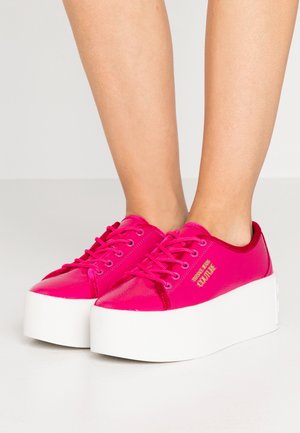 Roze platform sneakers met een glanzende afwerking, voorzien van een ronde neus, witte zool en opvallende veters. Opvallende merkidentificatie aan de zijkant.