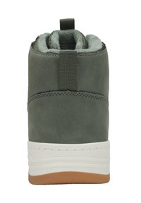 Grüner Knöchelstiefel aus Wildleder, mit einem weichen Futter, einer Zuglasche hinten und einer weißen Sohle mit einer braunen Gummisohle.