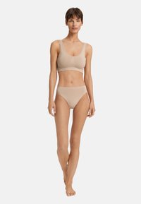 Beige bralette ja vastaavat bikinityyliset alushousut. Sileä pinta, joustava kangas ja leveät hihnat, joissa on yksinkertainen, minimalistinen muotoilu.