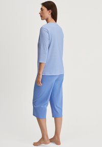 Blauwe gestreepte T-shirt met 3/4 mouwen, gecombineerd met effen blauwe cropped broek, beide gemaakt van zachte materialen. Geen patronen of hardware zichtbaar.