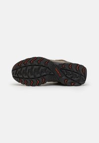 Hiking shoe sole features a rugged black rubber design with orange accents and deep treads for enhanced grip on varied surfaces.