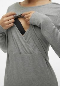 Grå långärmad topp i ribbat material, med en omslagsdesign och v-ringning som blottar en svart BH underneath.