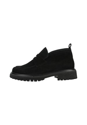 Mocasín negro de ante con suela de goma gruesa, tacón bajo y tira para tirar en la parte trasera, mostrado de perfil sobre un fondo blanco.