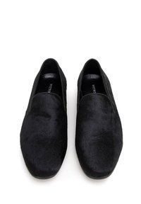 Czarne buty wsuwane, wykonane z gładkiego, teksturowanego materiału, z zaokrąglonym przodem i płaską podeszwą. Charakteryzują się minimalistycznym designem i brakiem widocznych elementów metalowych.