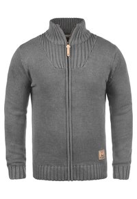 Cardigan grigio in maglia con colletto alto, chiusura a zip, polsini e orlo a coste. Presenta una toppa in pelle con logo sulla parte anteriore inferiore.