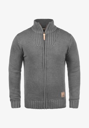 Hallidebe kootud cardigan kõrge kaelusega, lukuga sulgemine, soonikkoes varrukad ja äär. Alumisel eespool asub nahast logo silt.