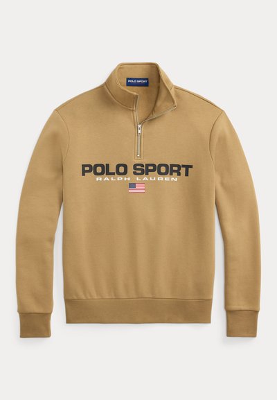 Kollane kangasüda, mis on valmistatud pehmest materjalist, millel on julged mustad tekstid "POLO SPORT" ja "RALPH LAUREN" koos Ameerika lipu aktsendiga.