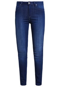 Pantalones vaqueros de denim azul con corte slim, que cuentan con cierre de cremallera y bolsillos frontales. La tela tiene una textura suave y un ligero desgastado.