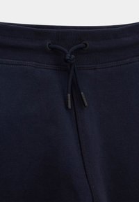 Marineblaue Baumwoll-Sweatpants mit verstellbarem Kordelzug am Bund, ausgestattet mit einer glatten Textur und verstärkten Nähten. Dezente Markenkennzeichnung an den Spitzen.