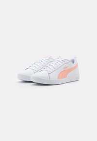Sneakers bianchi con accenti rosa, tomaia in pelle sintetica, punta rotonda, design con lacci, collo imbottito e suola in gomma testurizzata.