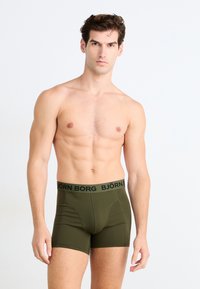 Olivové boxerky s čiernym pásom, na ktorom je logo "BJÖRN BORG". Vyrobené z elastickej tkaniny, priliehavý strih so švovými detailmi.