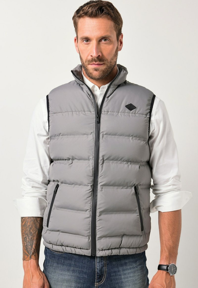 Graue Steppweste mit hohem Kragen, ausgestattet mit einem Frontreißverschluss und seitlichen Taschen. Besonders auffällig ist die gesteppten Textur und die schwarzen Akzente.