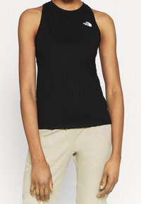 Svart ärmlös linne i mjukt tyg, med hög halsringning och en liten vit logotyp på vänster bröst.