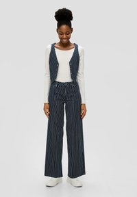 Gestreiftes Outfit mit einem Marineblauen und weißen Weste sowie weiten Hosen. Hergestellt aus einem glatten Stoff, mit Knopfdetails und lockerer Passform.