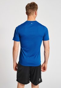 Blå atletisk t-shirt lavet af letvægts, fugttransporterende stof, med korte ærmer og rund halsudskæring, parret med sorte shorts.