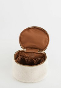 Rund, hvid kosmetiktaske i kunstig fåreskind med brun satinindvendig, lynlåslukning og indvendig elastiklomme til organisering.