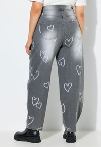 Grå, højhalset denimjeans med hvide hjerteprint, løs pasform, fem lommer og sorte chunky støvler.