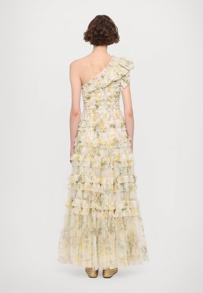 Een one-shoulder, gelaagde lange jurk van doorschijnende pastelstof met bloemenpatronen; heeft ruches en een aansluitend lijfje.