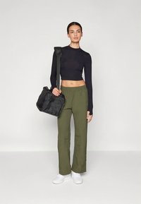 Čierny crop top s dlhým rukávom, olivovo zelené široké nohavice, biele tenisky a čierna kabelka na rameno. Jednoduchý dizajn, hladká textúra, ležérny vzhľad.