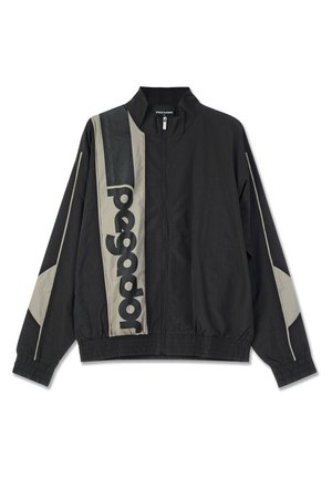 Juodas lengvas švarkas su pilkomis detalėmis, turintis aukštą apykaklę, elastines rankoves ir didelį logotipą priekyje. Sklandus tekstūra, užtrauktuko uždarymas.