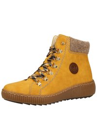 Bottes montantes en cuir jaune avec des détails bruns, œillets en métal, lacets à carreaux noir et jaune, et une semelle en caoutchouc texturée.