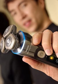 Rasoi Philips con tre teste metalliche rotonde, corpo argentato e nero, accenti blu illuminati e pulsante di controllo con luce arancione.
