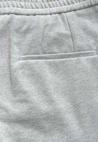 Pantaloni corti in tessuto grigio chiaro con una texture orizzontale, vita elastica e una tasca a filetto sul retro.