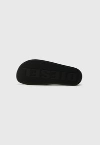 Black rubber shoe sole featuring textured surface, curved shape, and engraved "DIESEL" branding.