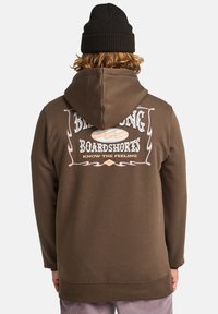 Sweat-shirt à capuche marron avec un logo graphique au dos, arborant "Billabong Boardshorts" et "Know the Feeling". Texture douce.