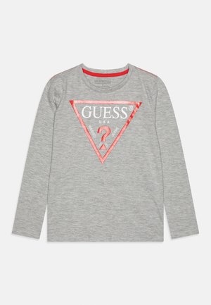 Šedé tričko s dlouhým rukávem s červeným trojúhelníkovým logem s nápisem "GUESS U.S.A." a velkým červeným otazníkem uprostřed.