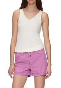 Weißes Ripp-Top mit V-Ausschnitt, kombiniert mit rosa Jeansshorts mit umgeschlagenen Säumen und Fronttaschen mit Knopfverschlüssen.