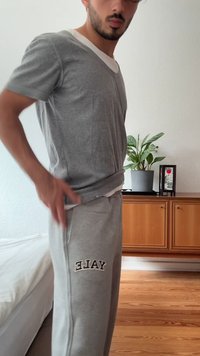 Pilkas trumpas rankovėmis marškinėlis su baltu apykaklės kraštu, derinamas su pilkomis sportinėmis kelnėmis, kurių kairiajame šone juodu siuvinėjimu užrašyta "YALE".