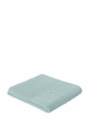 Couverture texturée bleu clair avec un coin plié et un détail de bouton pression, mettant en valeur un motif tissé et une apparence douce.