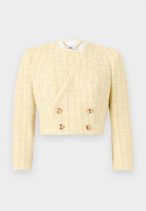 Střihnutá žlutá tvídová bunda s dlouhými rukávy, dvojřadovými zlatými knoflíky a detailními vroubkovanými výstřihy.