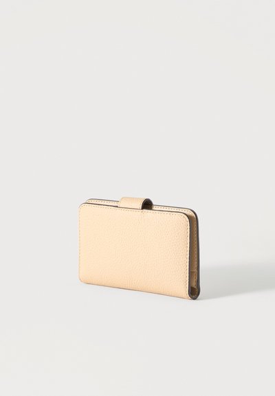 Portefeuille en cuir beige texturé avec fermeture à pression, debout sur un fond gris clair.