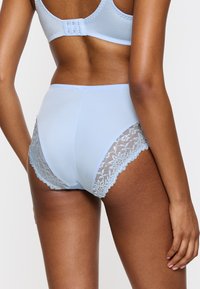 Jasnoniebieskie figi z wysokim stanem, zdobione koronkowymi akcentami po bokach oraz gładkim, elastycznym materiałem głównym zapewniającym komfort.