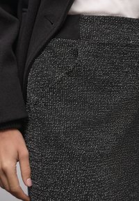 Musta teksturoitu housut hienovaraisella kuviolla, sivutaskulla ja joustavalla vyötärönauhalla mukavuutta varten. Hienosti kudottu materiaali.