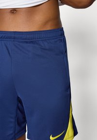 Marine athletic shorts lavet af fugtbevarende stof. Har en tekstureret overflade, elastisk talje og et lyst gult Nike logo.