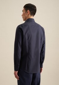 Marineblauwe longsleeve shirt met een omgeklapte kraag, een gladde textuur, knopenmanchetten en een licht gebogen zoom aan de achterkant.