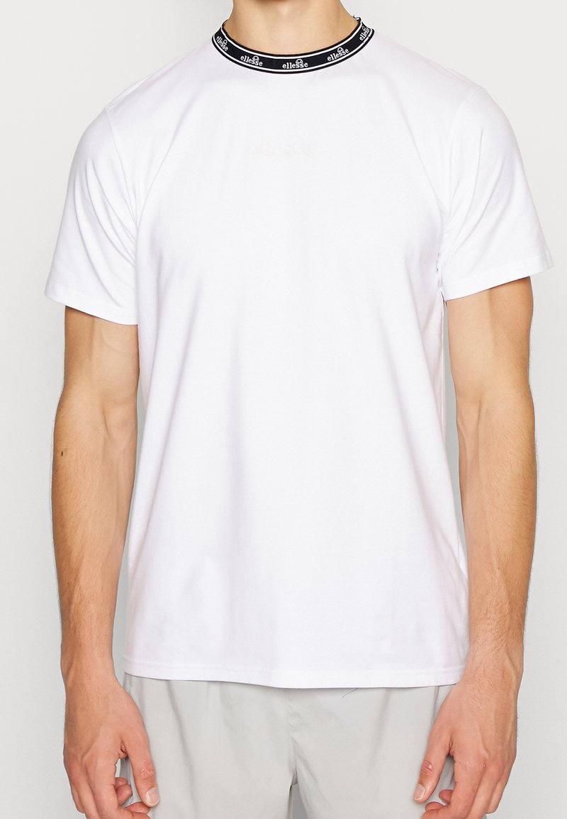 Camiseta blanca de manga corta con cuello negro que presenta el nombre de la marca. Tela suave y corte relajado, adecuada para el uso diario.