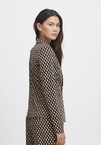 Karierter Blazer in Schwarz und Tan, strukturierte Form, glatte Textur, einreihiger Knopfverschluss, mit Reverskragen und Fronttaschen.