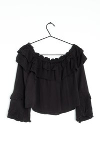 Blusa nera off-the-shoulder appesa a un gancio, con dettagli a volant, maniche lunghe con polsini elasticizzati e un design ampio e leggero.