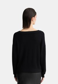 Maglione nero oversize con un ampio scollo a spalle scoperte, polsini e orlo a coste. Tessuto morbido e vestibilità ampia. Design semplice, senza motivi.